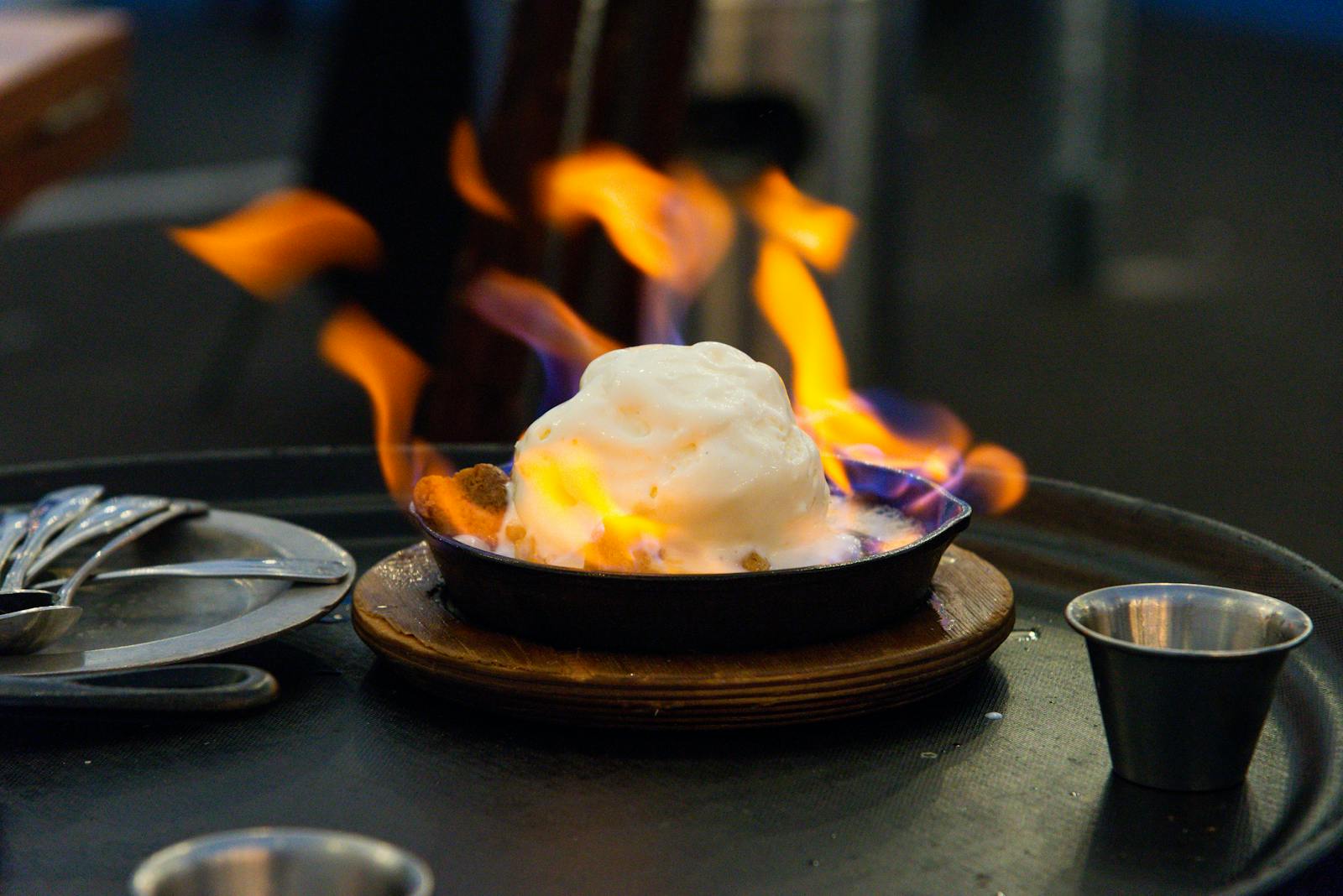 Close-up of a flaming dessert on a restaurant table, showcasing vibrant colors.